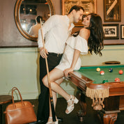 Man and woman in formal attire posing by a pool table in an elegant room.